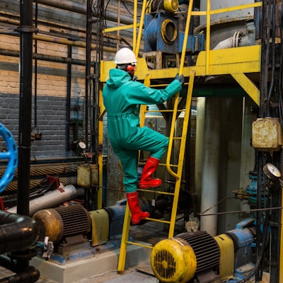 a man in a green coverall climbing up a yellow ladder