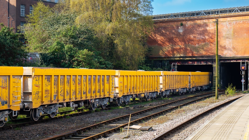 a yellow train traveling down train tracks next to a tall building