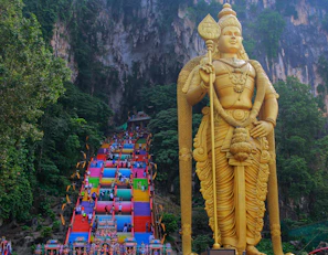 a large statue of a god in front of a mountain