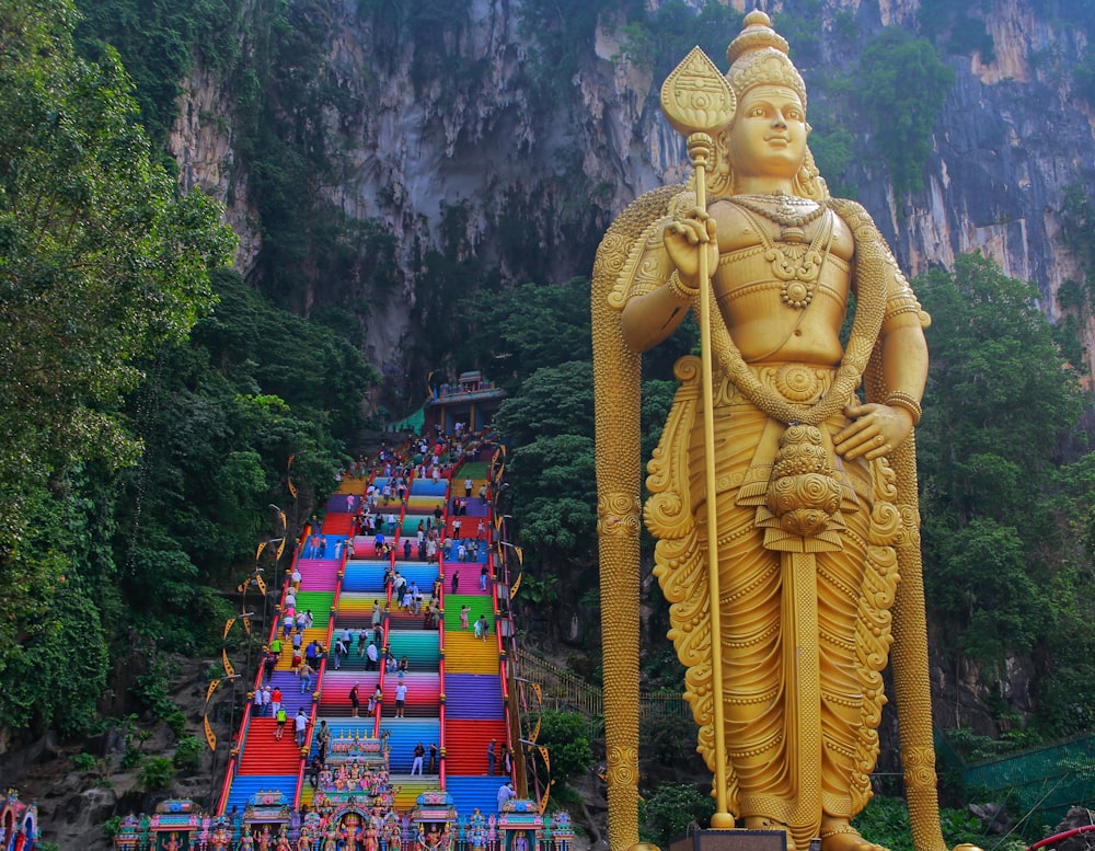 a large statue of a god in front of a mountain