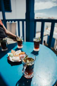 Warm morning light streaming through blue-tinted windows onto a rustic wooden table set with tea and falafel.
