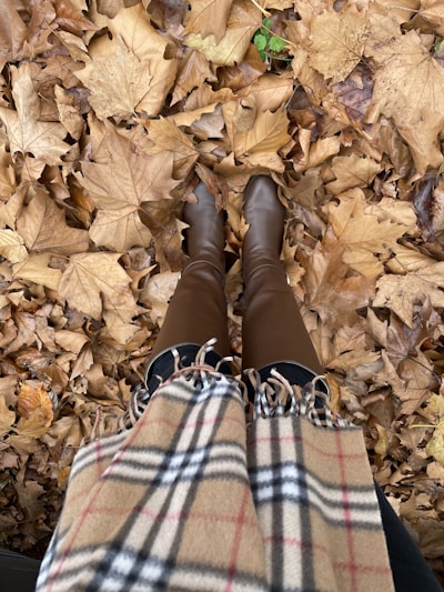 A vibrant street style shot featuring a layered autumn outfit with cozy scarves and bold boots.