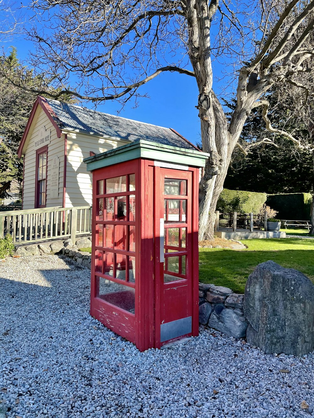 a red phone booth sitting on top of a gravel field