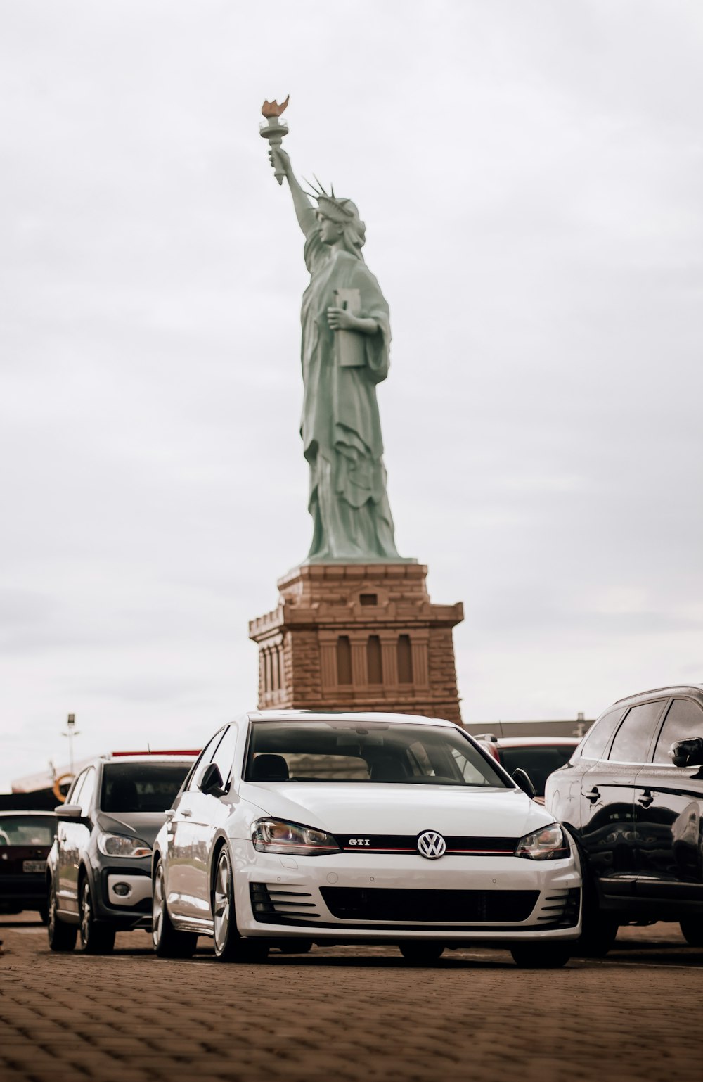 cars parked in front of the statue of liberty