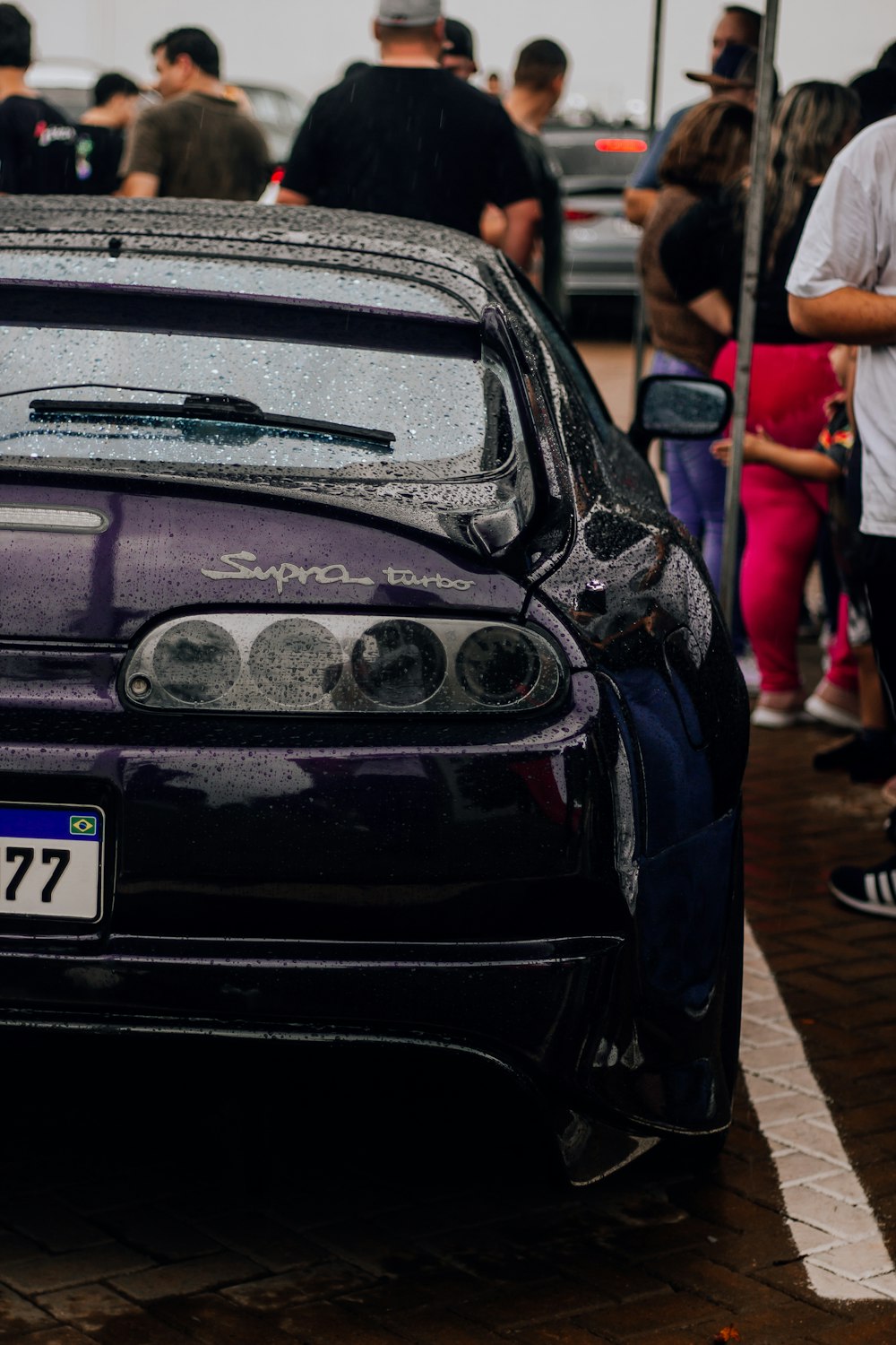 a purple car parked in front of a crowd of people