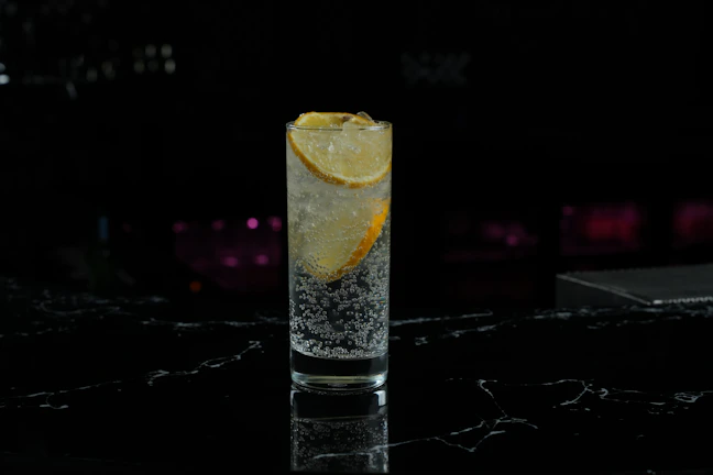 A colorful generation spritz pouring into a tall glass filled with ice and topped with sparkling bubbles.