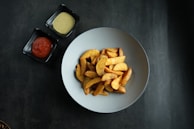 An assortment of potato wedges served with a variety of dips.