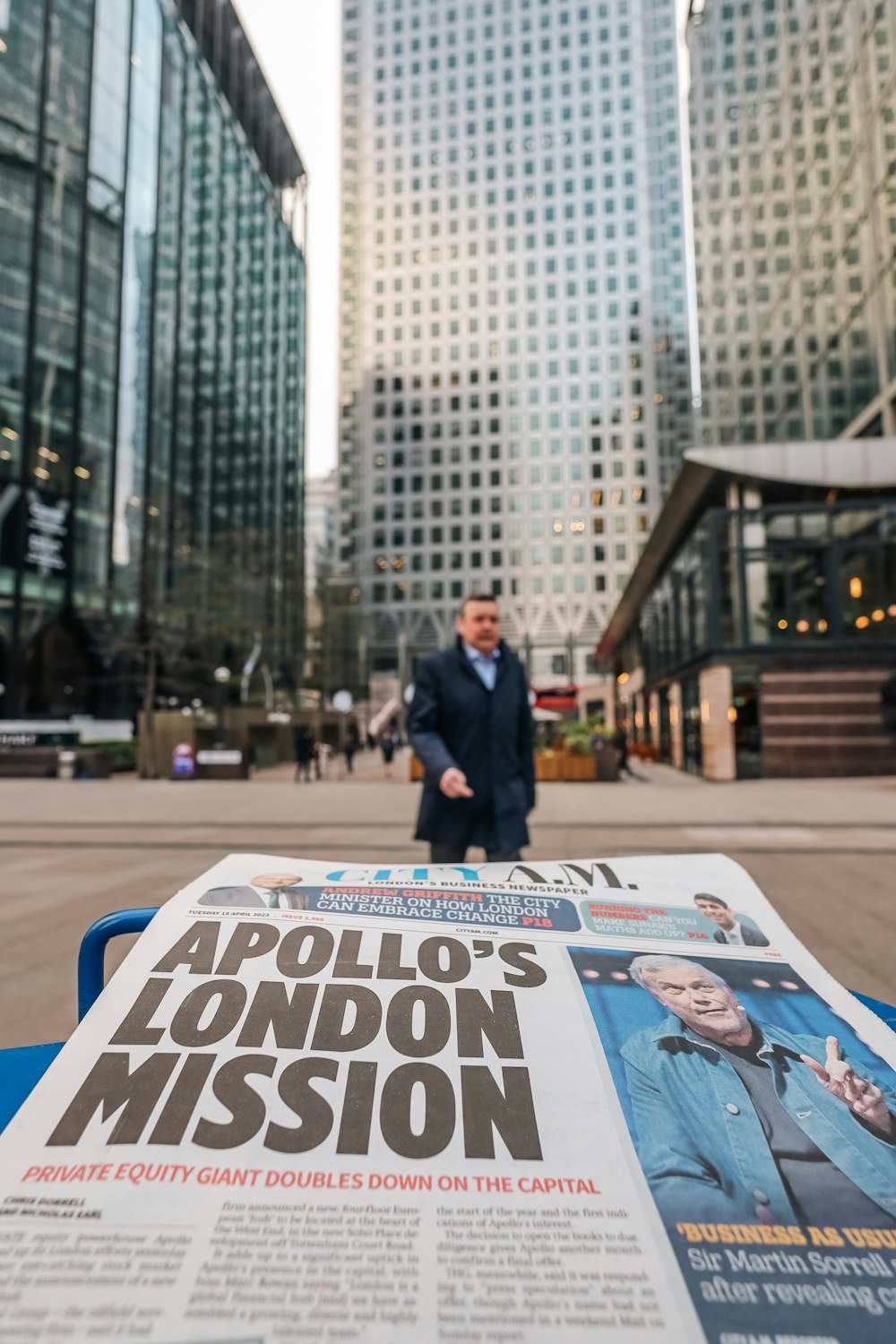 a man in a suit walking past a newspaper