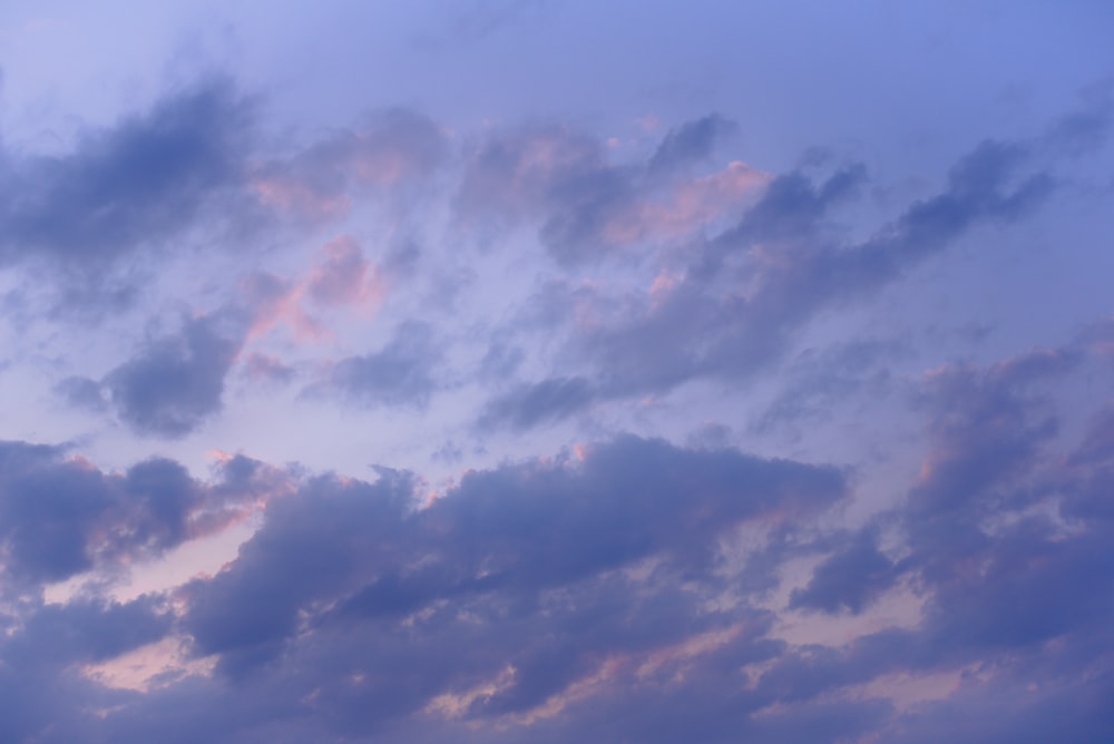 a plane flying through a cloudy blue sky