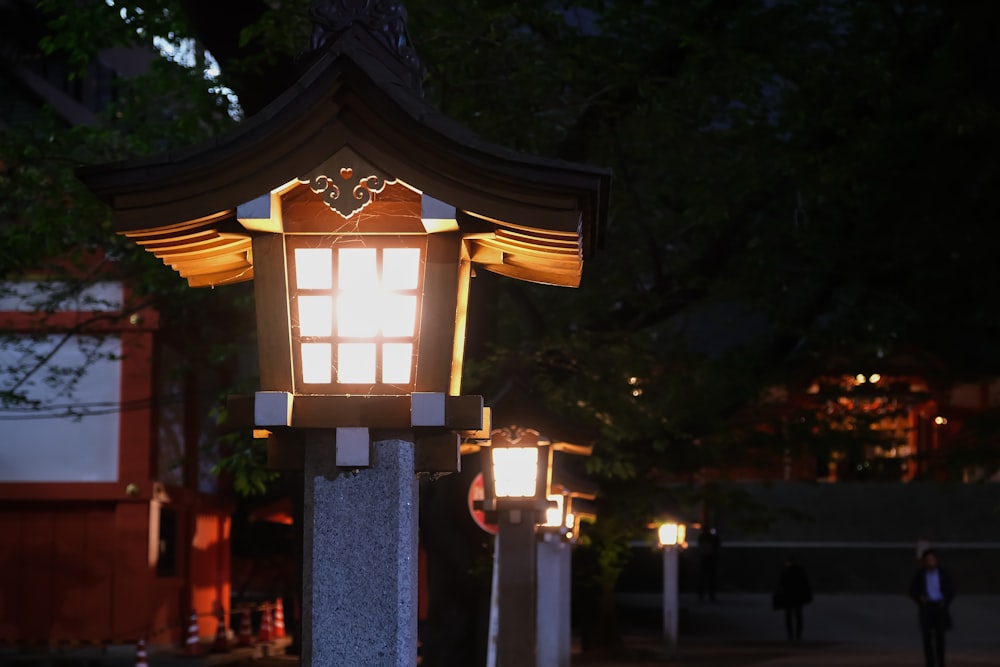 a lantern lit up in the night with people walking by
