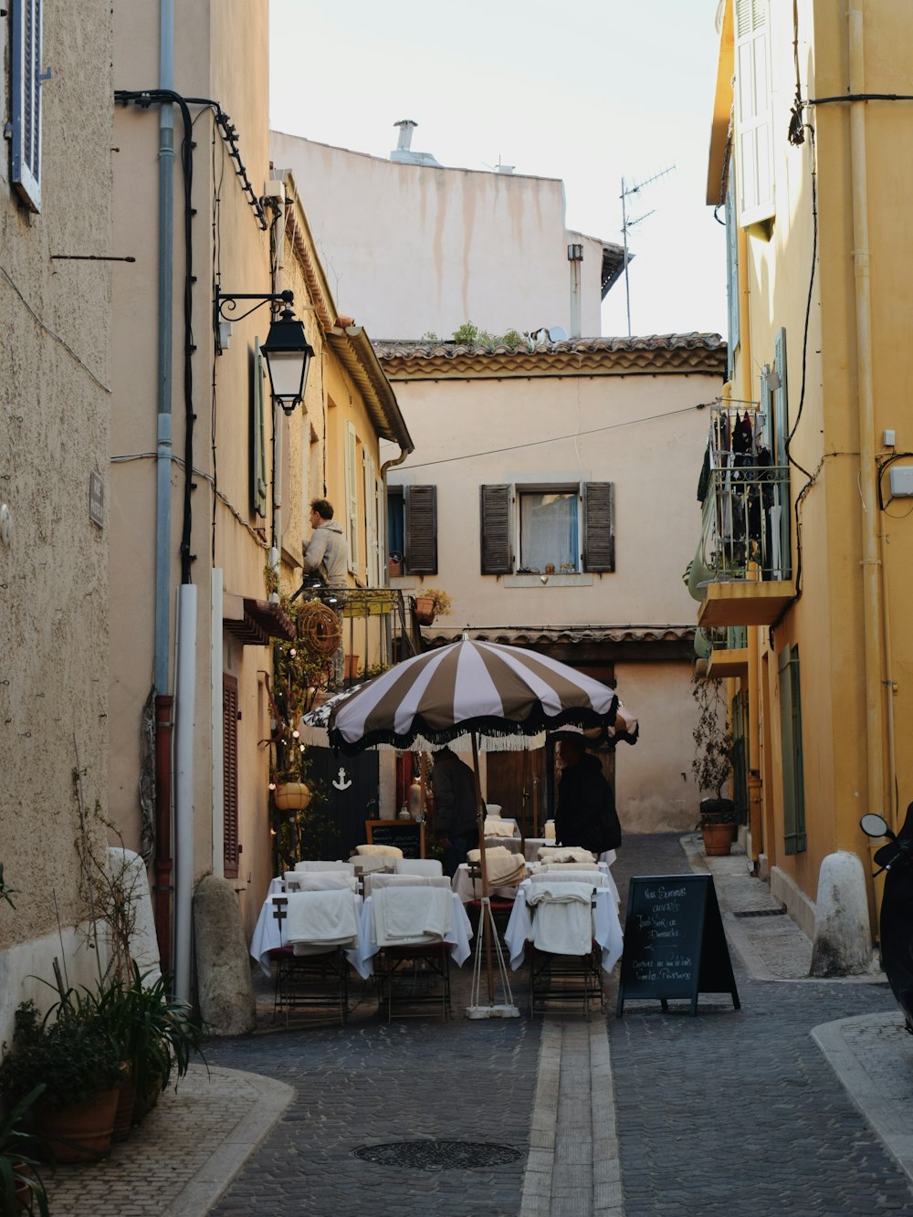 a narrow alleyway with tables and umbrellas