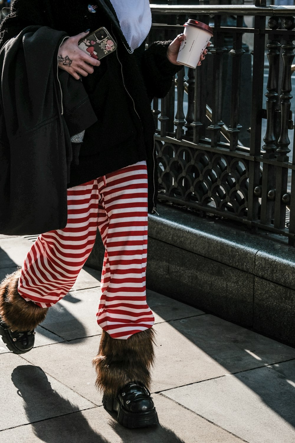 a person in striped pants and furry boots walking down a sidewalk