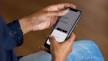 A person is holding a smartphone displaying a currency converter app. The screen shows conversion rates between GBP and EUR, with corresponding amounts.