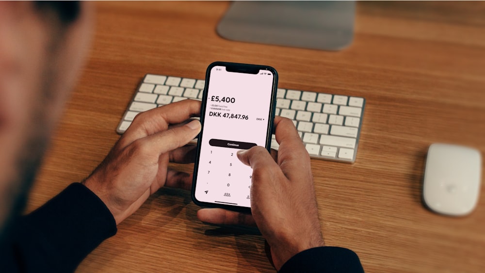 un uomo che tiene un telefono cellulare davanti a una tastiera