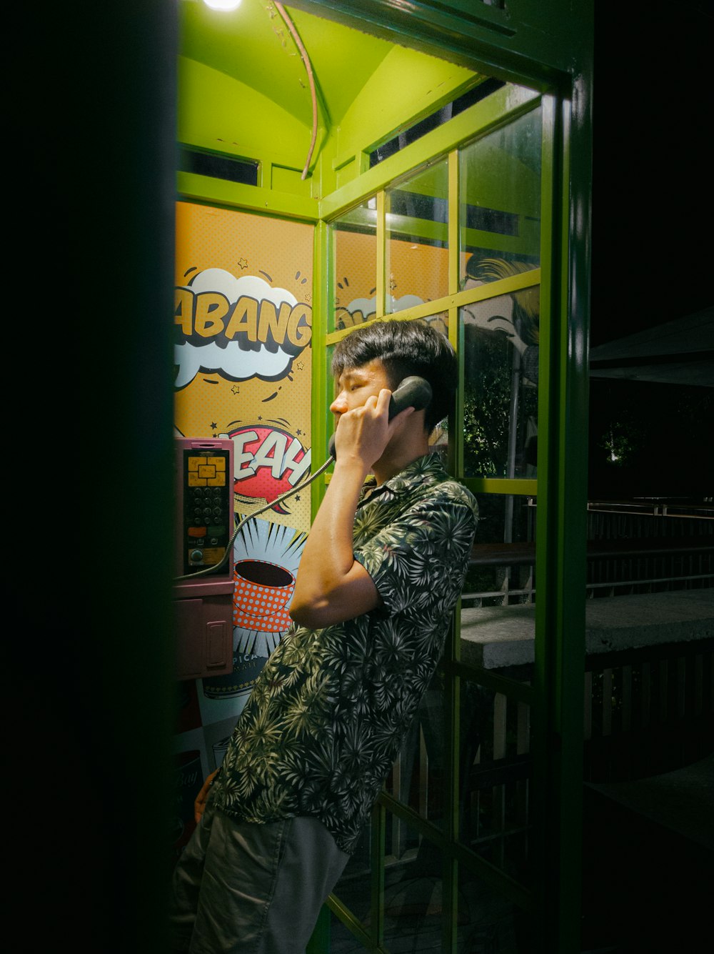 a man talking on a cell phone while standing in a booth