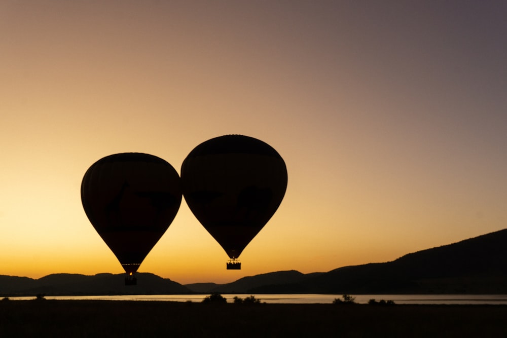 a couple of hot air balloons flying over a lake
