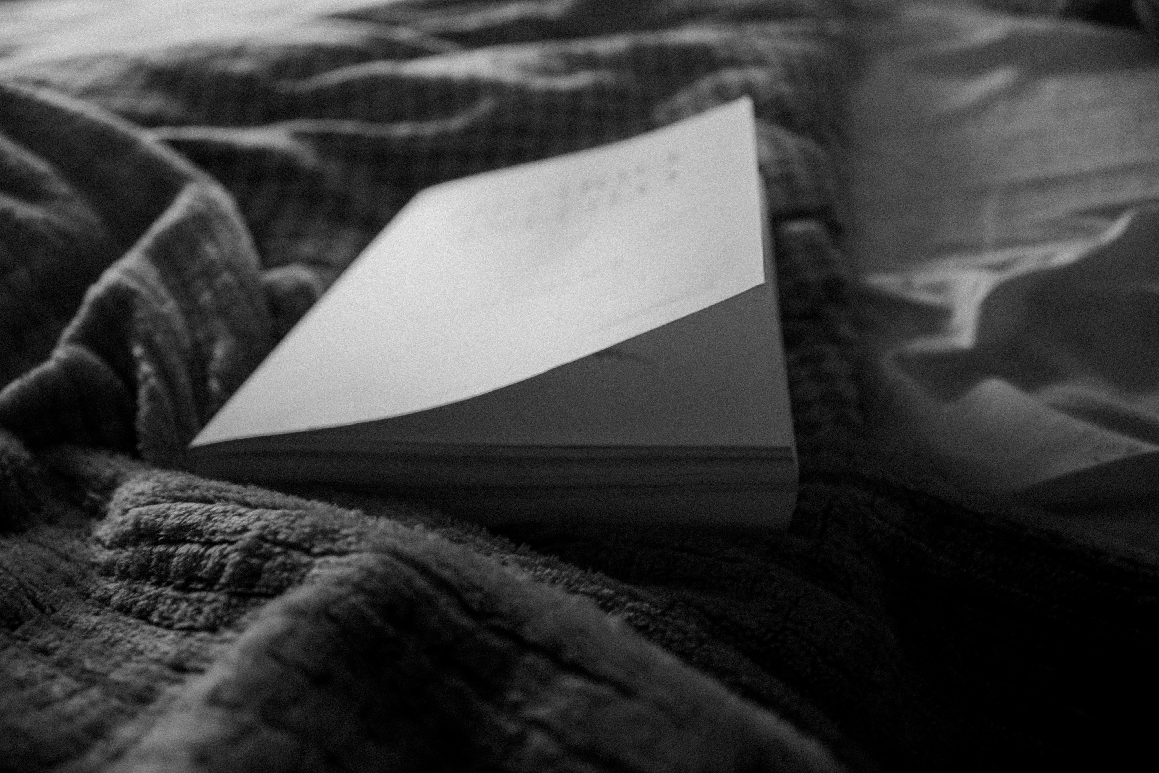 a black and white photo of a book on a bed