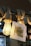 A glowing light bulb hangs next to a piece of rope wrapped around a metal bar. A square card with the word 'STORY' printed on it hangs beside the bulb, partially illuminated by its light. The background appears to be the interior of a room with blurred details, suggesting a cozy atmosphere.