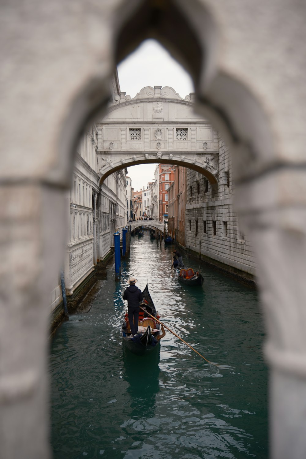 a man riding a boat down a canal under a bridge