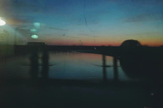 A sleek, modern glass panel with soft shadows showcasing a serene sunset over a calm ocean, reflecting the luxurious and tranquil vibe of vialuxe.