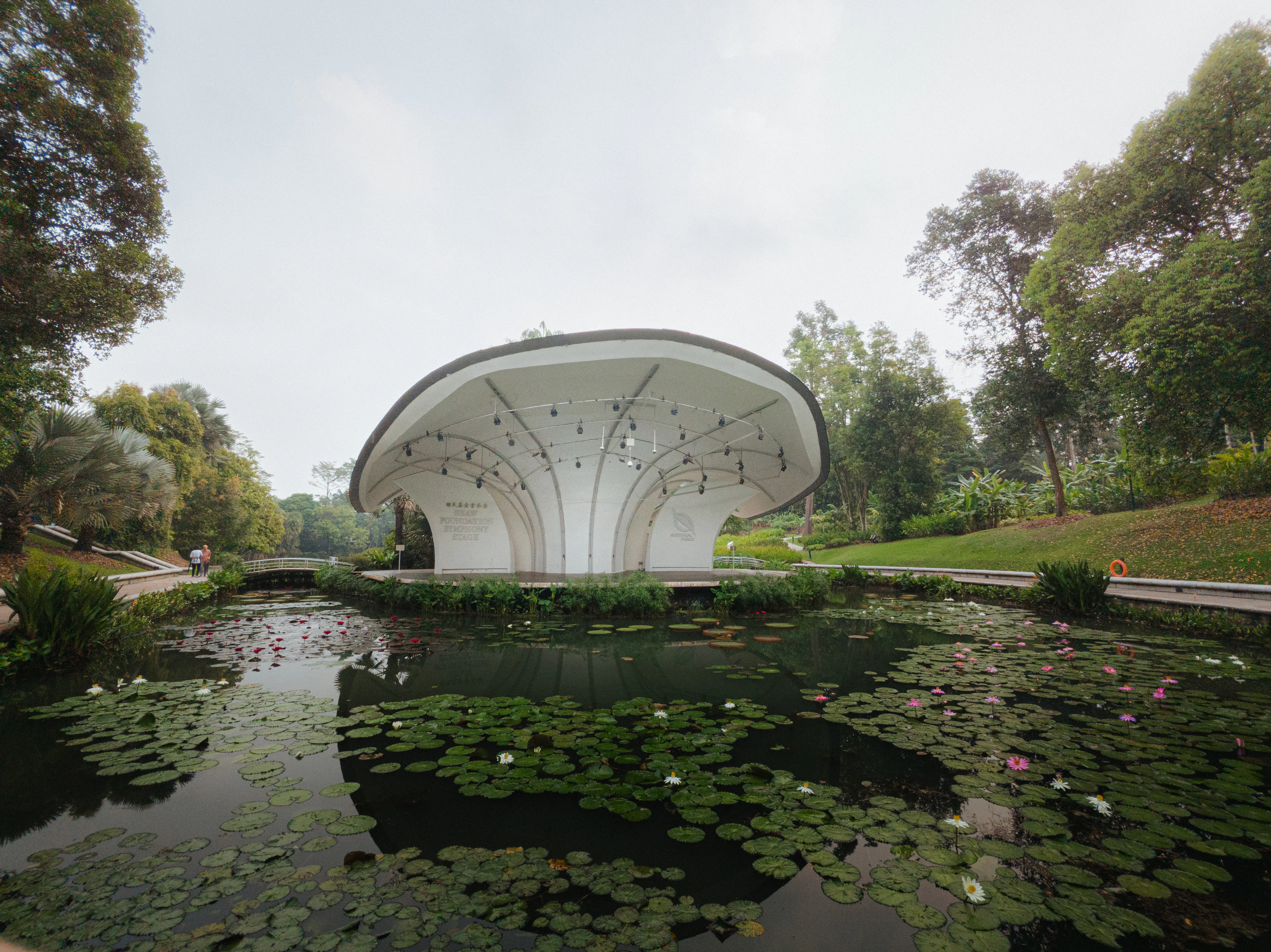 The white, shell-shaped Symphony Stage beside a lily-covered lake in the Singapore Botanic Gardens