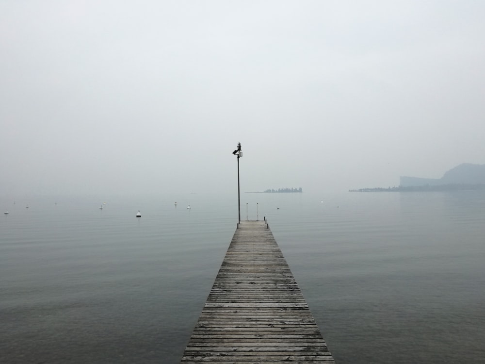 a long dock extending into the ocean on a foggy day
