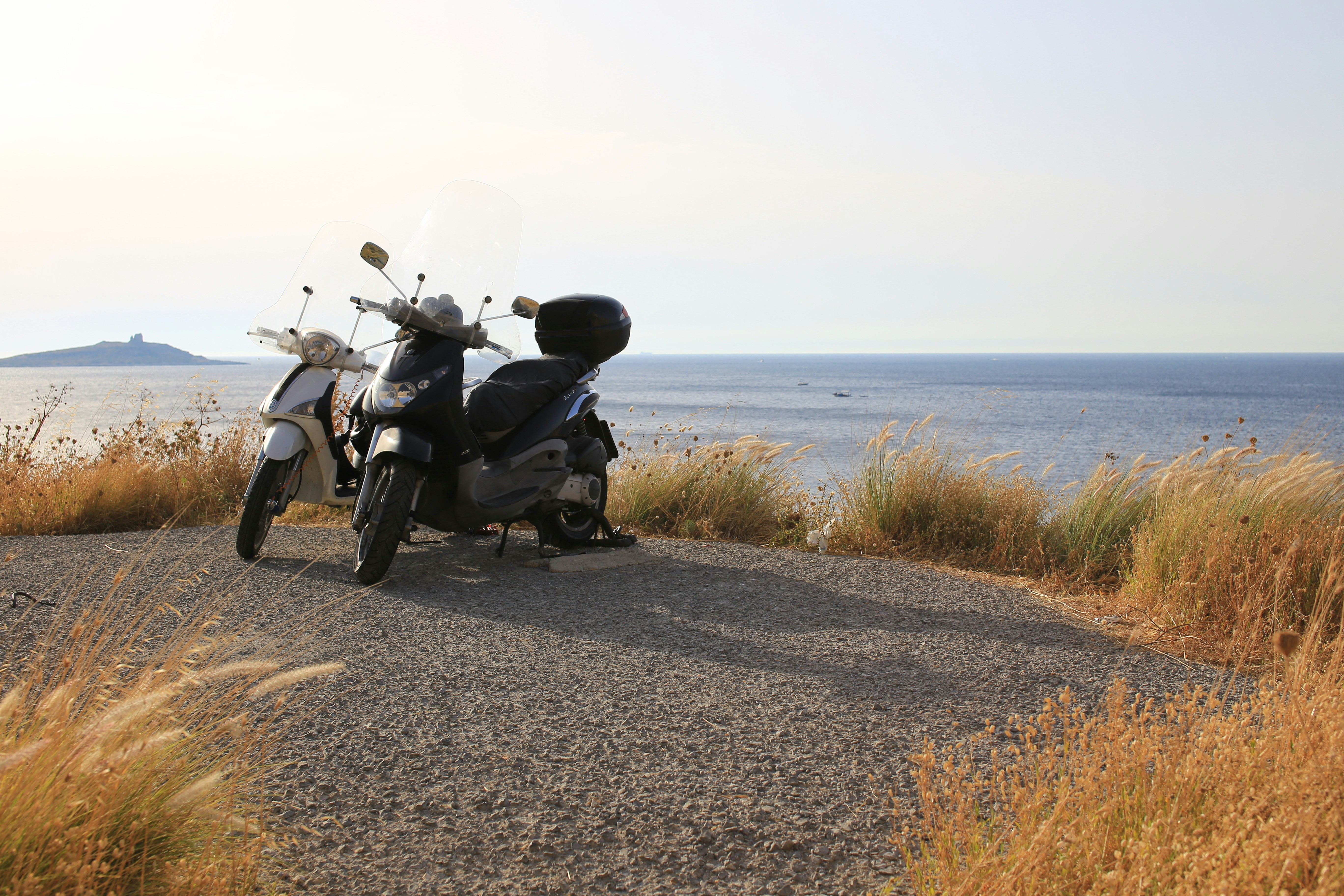 a scooter parked on the side of a road near the ocean