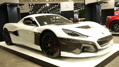 A futuristic electric car showcased under bright lights at a tech expo.