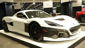 Sleek electric hypercar gliding on a coastal road at sunset, showcasing atom motors' power.