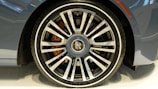 A close-up of a polished luxury car wheel shining under bright daylight.