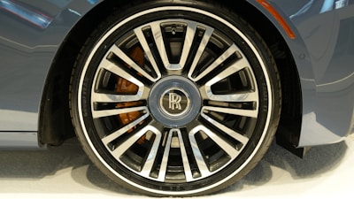 A close-up of a polished luxury car wheel shining under bright daylight.