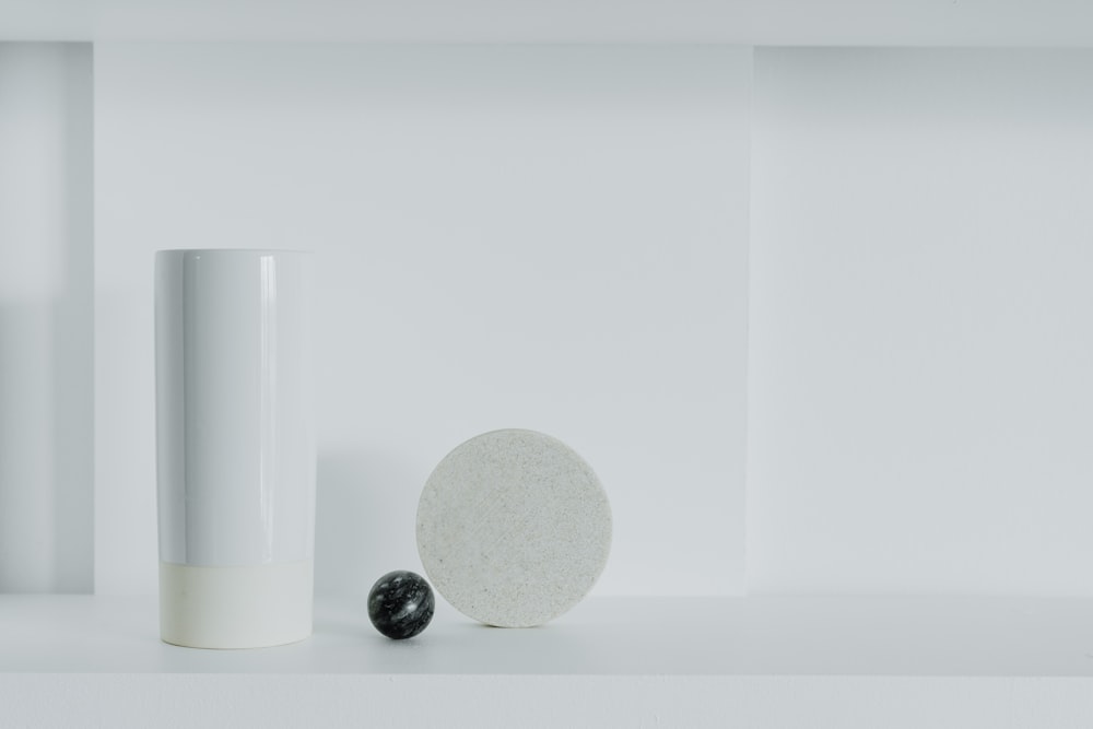 a white vase sitting next to a black and white object