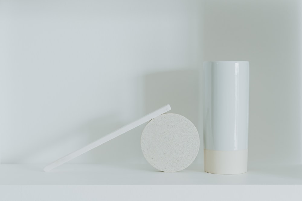 a white vase sitting next to a white round object