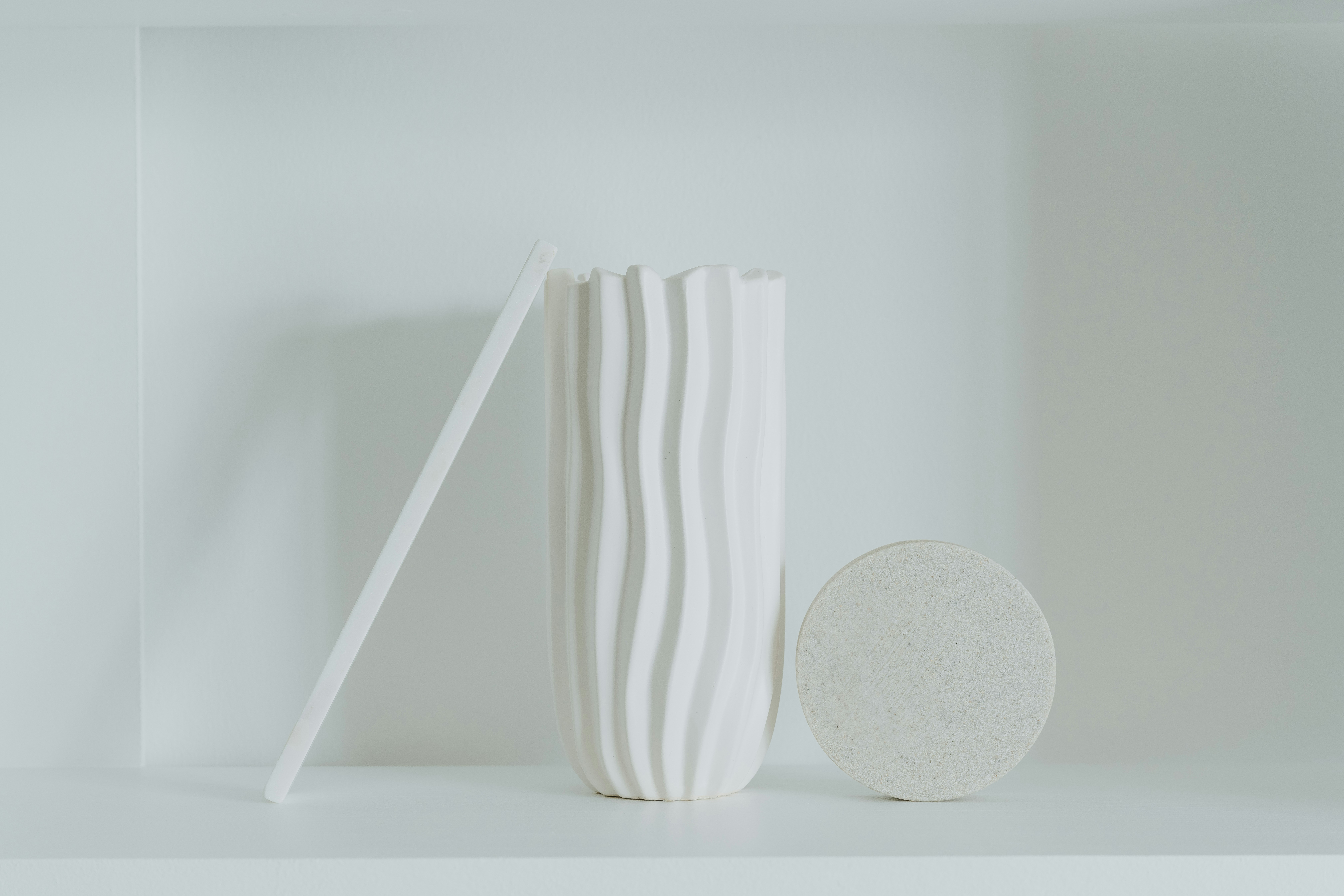 a white vase sitting on top of a white shelf