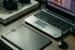 A workspace featuring a laptop with photo-editing software open, a graphics tablet, a digital pen in a holder, and a box labeled 'Wacom Intuos Pro.' Additionally, there's a DSLR camera resting on the box.