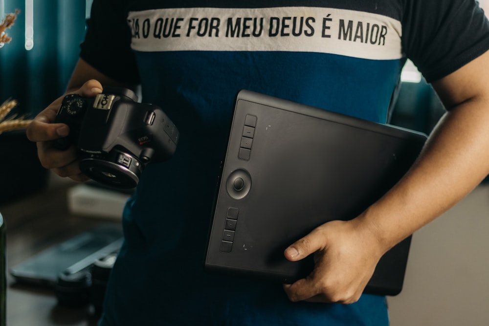 a man holding a camera and a laptop