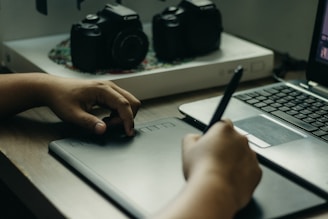 a person sitting at a desk with a laptop and a pen