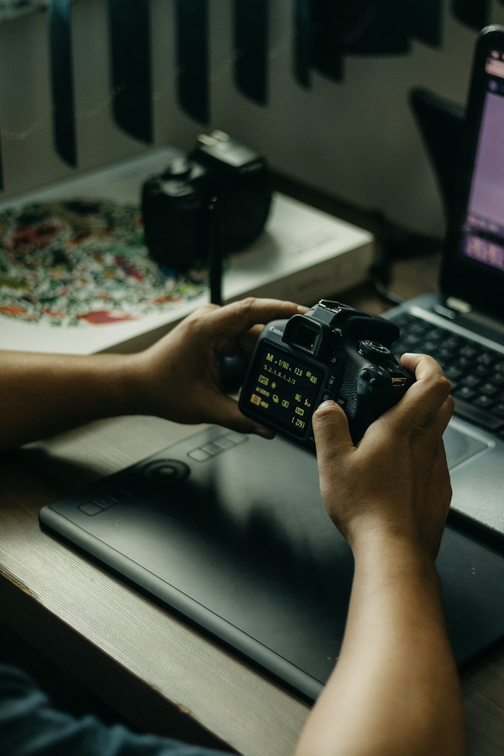 a person holding a camera in front of a laptop