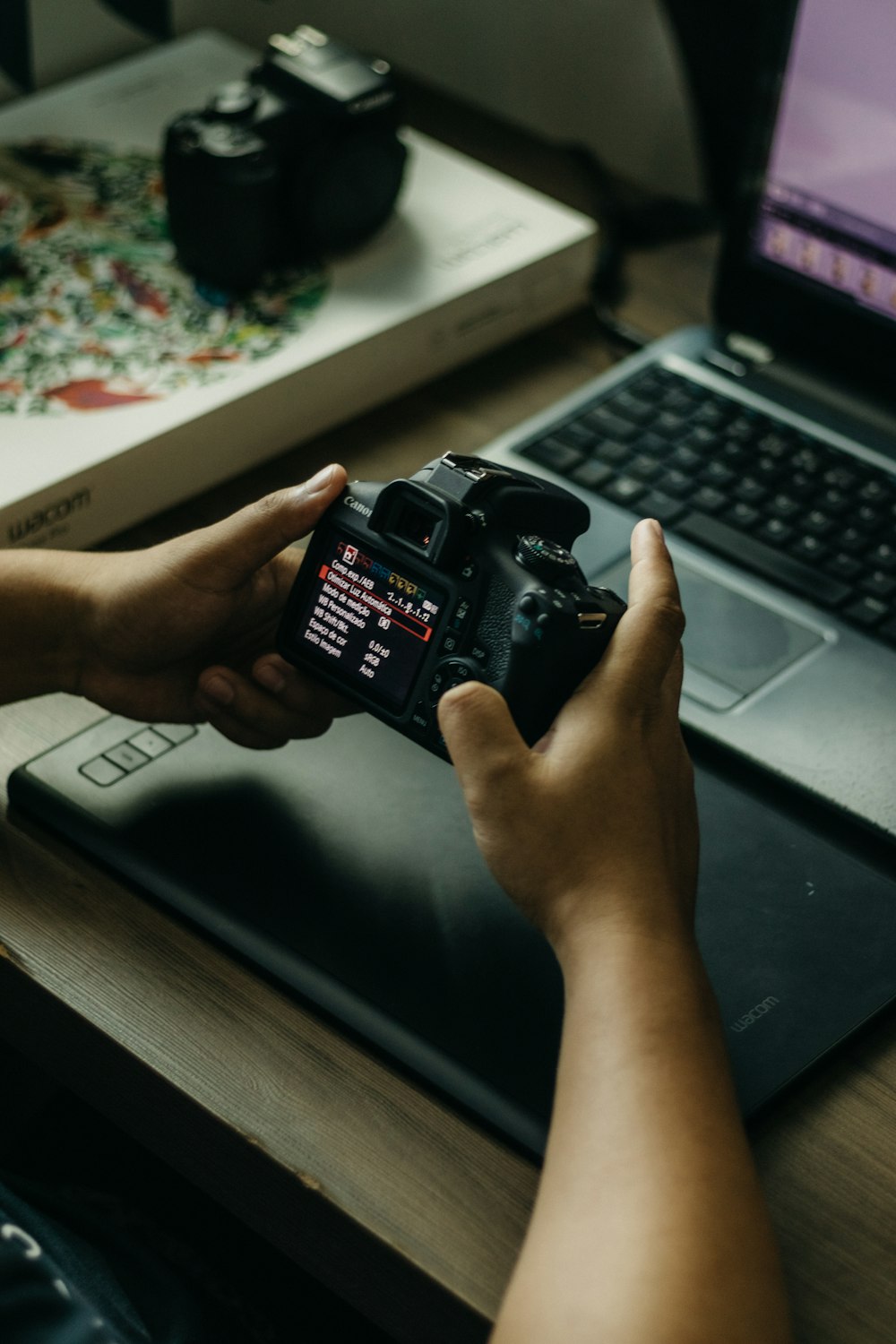 Una persona sosteniendo una cámara frente a una computadora portátil