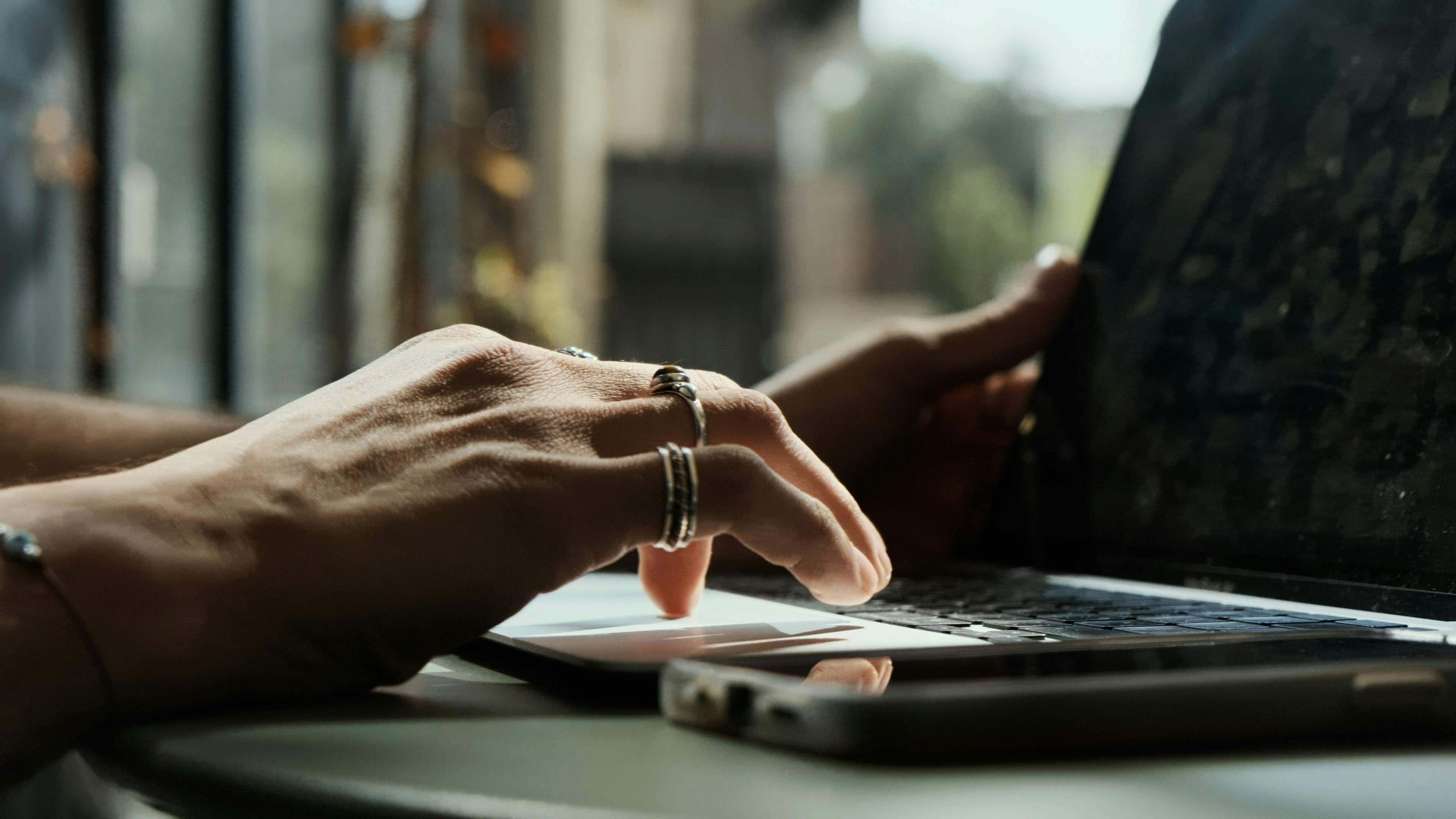 Hands typing on a laptop displaying a video editing timeline, illustrating the craft of impactful visual storytelling through precise language.