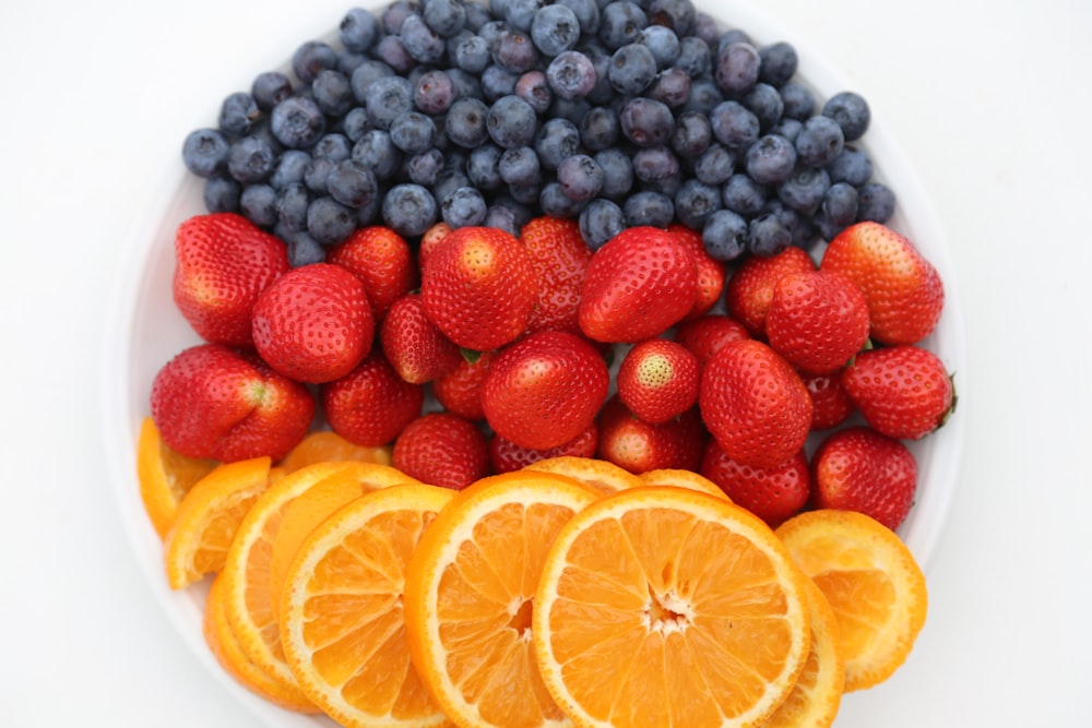 a white plate topped with oranges, blueberries and strawberries