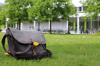 A rugged messenger bag placed on a city sidewalk with soft sunlight.