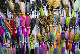 a bunch of different colored brushes hanging on a wall