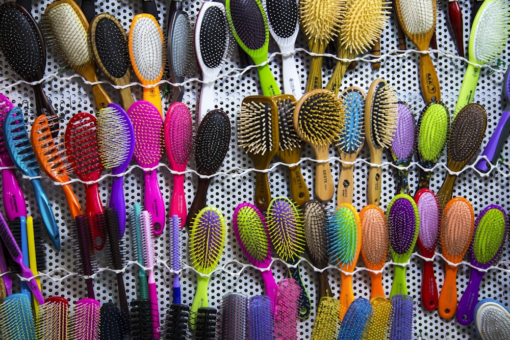 a bunch of different colored brushes hanging on a wall