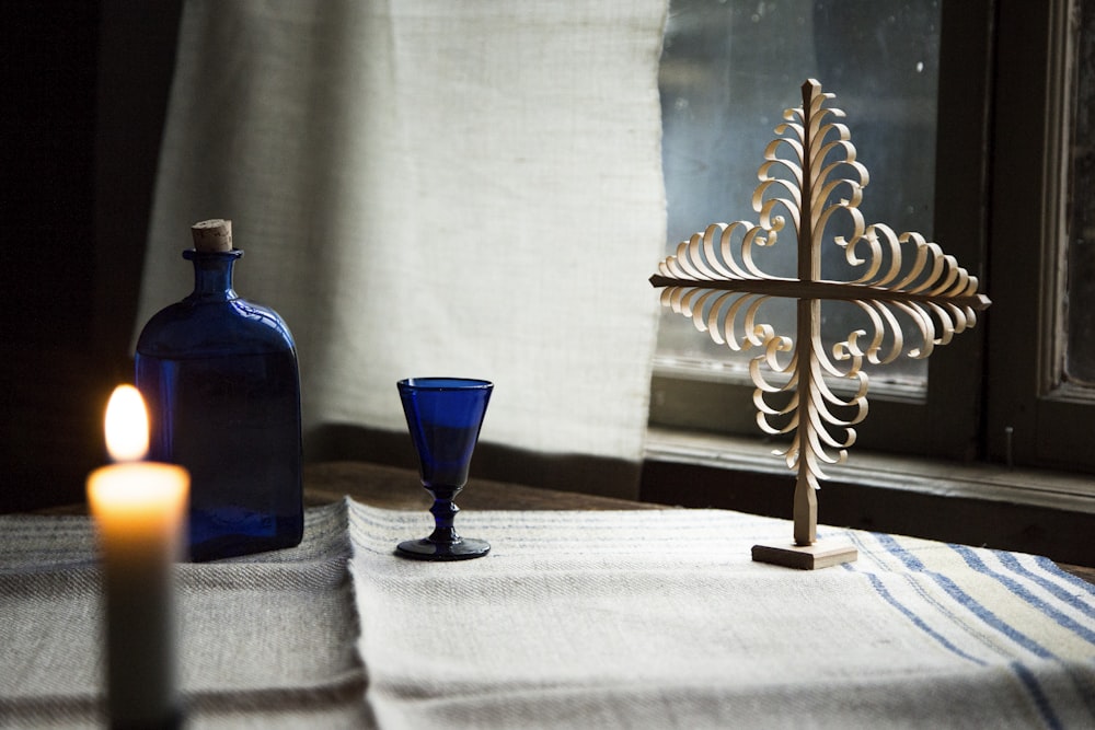 a candle and a blue glass on a table