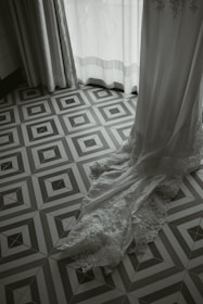 A wedding dress carefully covered and hanging in a softly lit room.