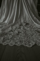 Close-up of fine lace detailing on a deep burgundy intimate robe, softly folded on a plush white surface.