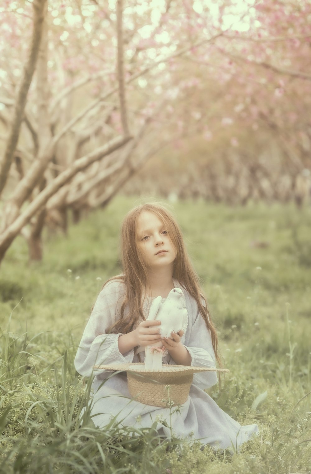 a little girl sitting in the grass with a basket