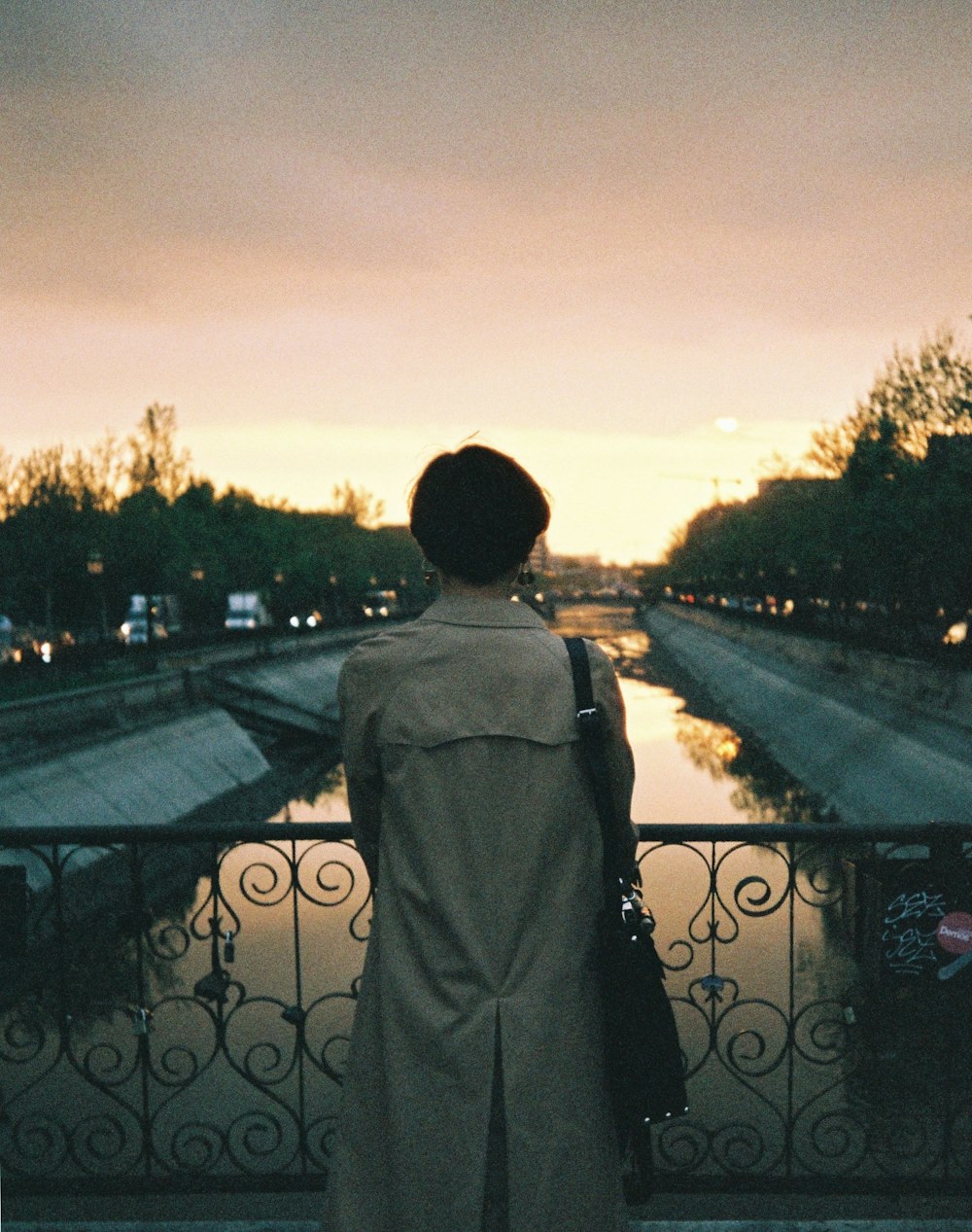 a woman standing on a bridge looking at the water