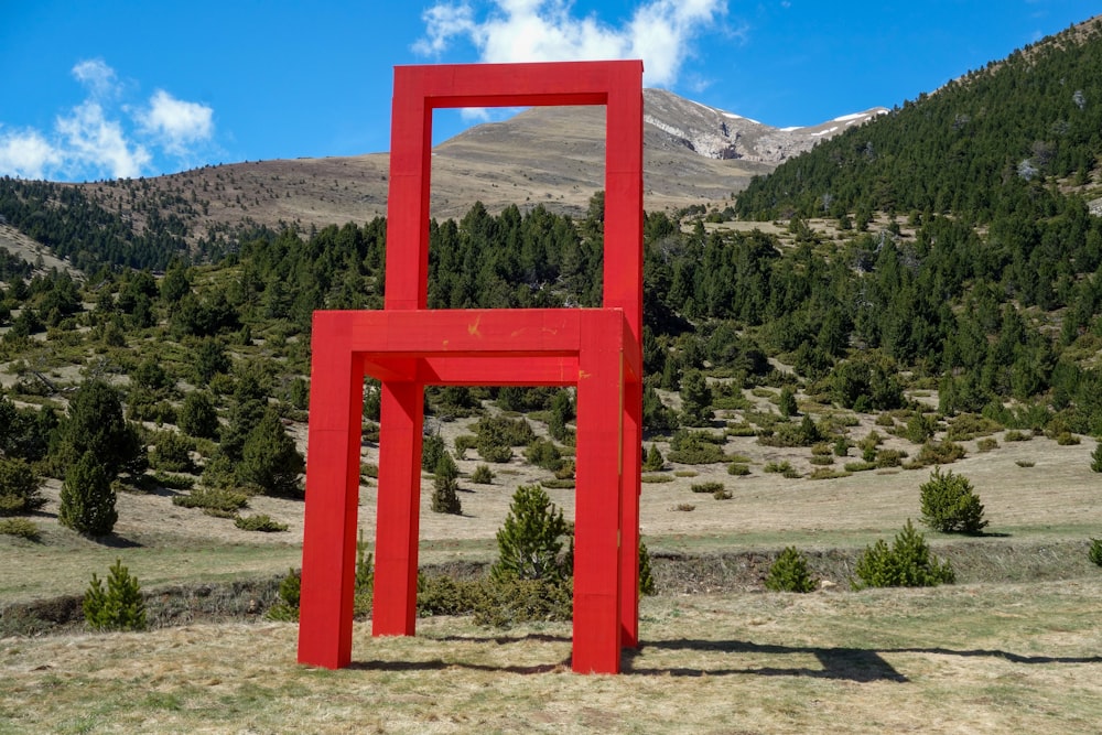 a large red chair sitting in the middle of a field